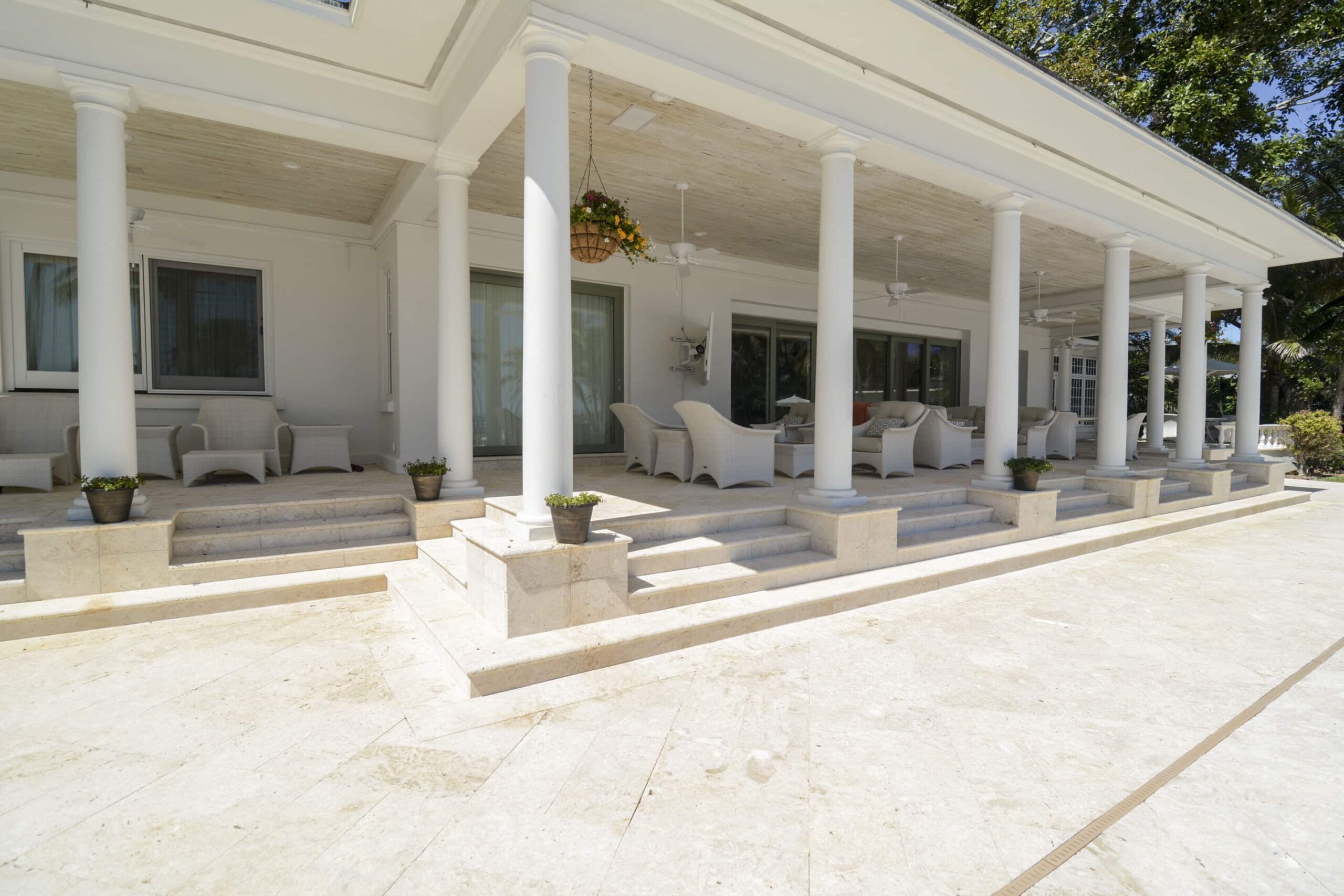 Exterior of home with beige natural stone paver patio and furniture.
