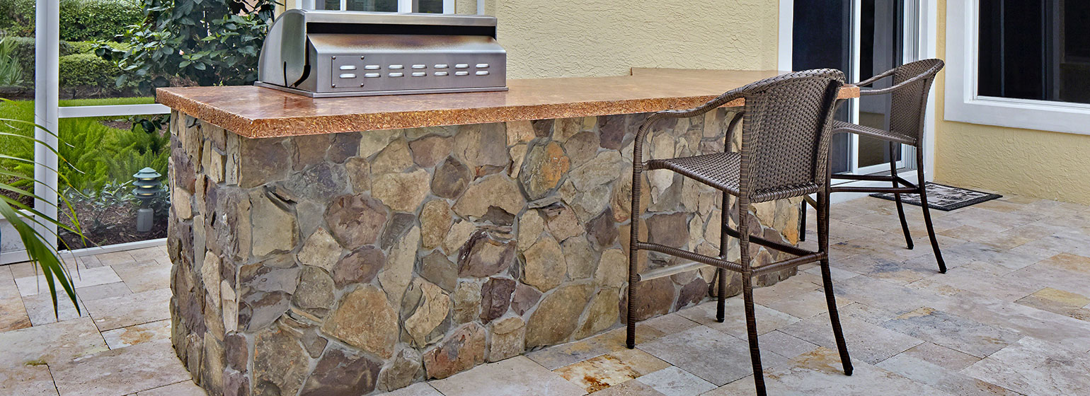 Small image of natural stone bar and outdoor kitchen area with stool.