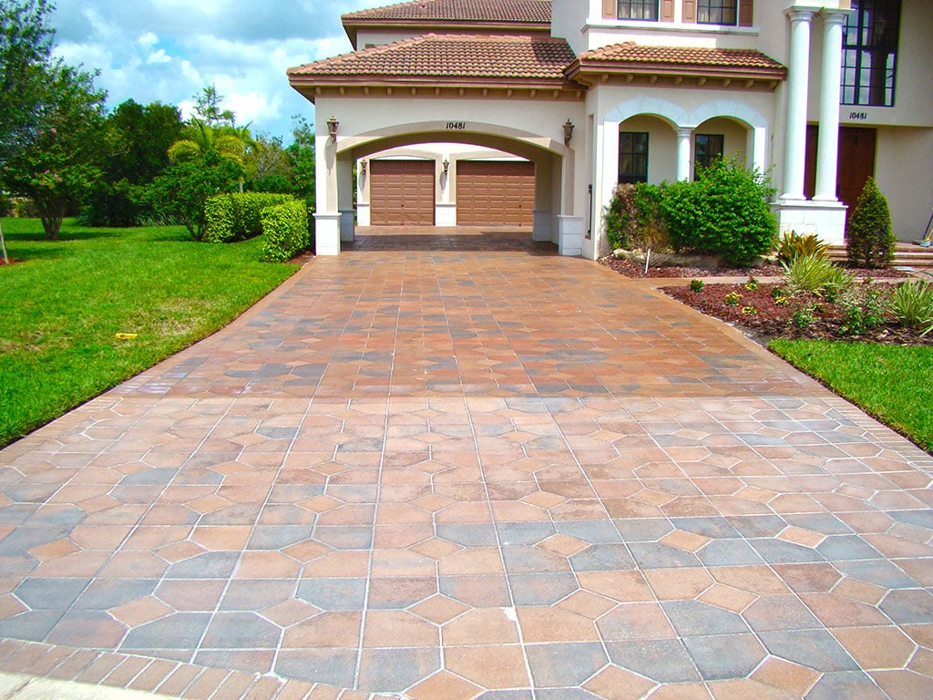 Tan and gray geometric paver driveway leading to two-stall garage.