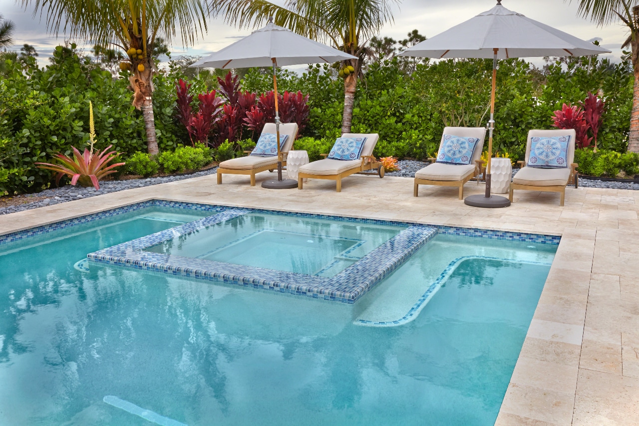 Large blue tile pool with in-pool spa/lounge area and chairs.